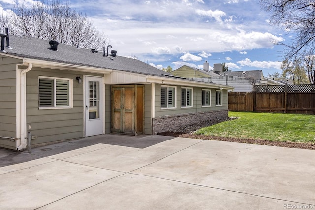 back of property with a lawn, a patio, fence, and a shingled roof