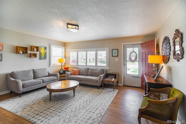 living area featuring baseboards, a textured ceiling, and wood finished floors