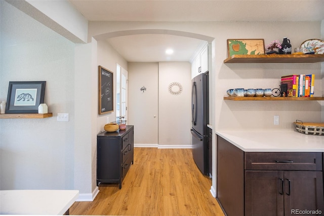 interior space featuring arched walkways, baseboards, and light wood-style floors