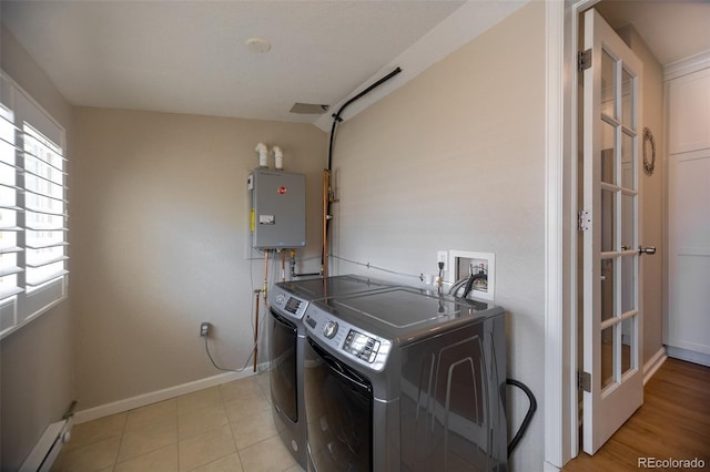 clothes washing area featuring separate washer and dryer, laundry area, baseboards, and a baseboard radiator