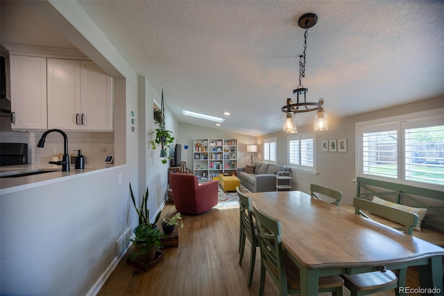 dining area featuring a textured ceiling, baseboards, wood finished floors, and lofted ceiling
