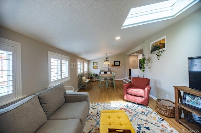 living room with baseboards, a textured ceiling, wood finished floors, and lofted ceiling with skylight
