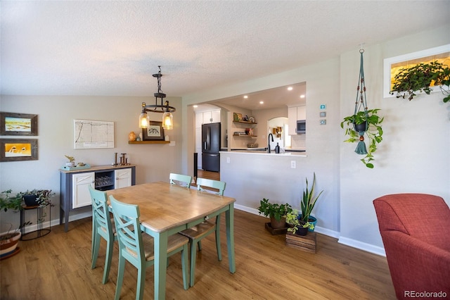 dining room with recessed lighting, baseboards, light wood-type flooring, and a textured ceiling
