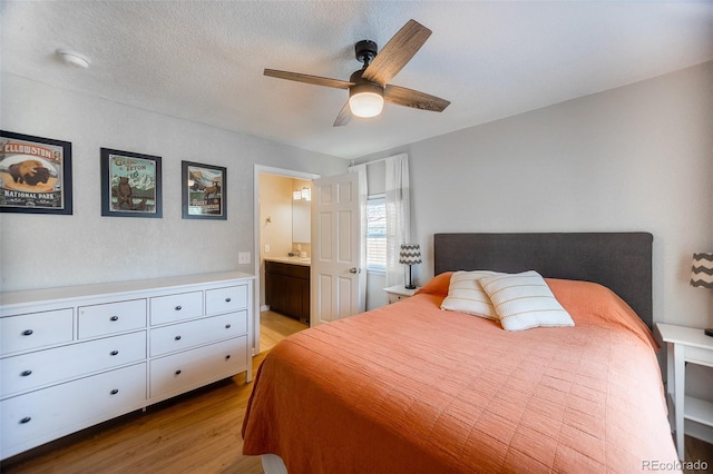 bedroom featuring light wood-type flooring, a ceiling fan, and ensuite bath