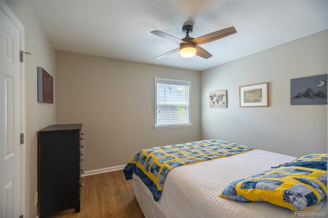 bedroom with a ceiling fan, baseboards, wood finished floors, and a textured ceiling