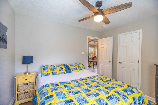 bedroom with a ceiling fan, arched walkways, and a textured ceiling
