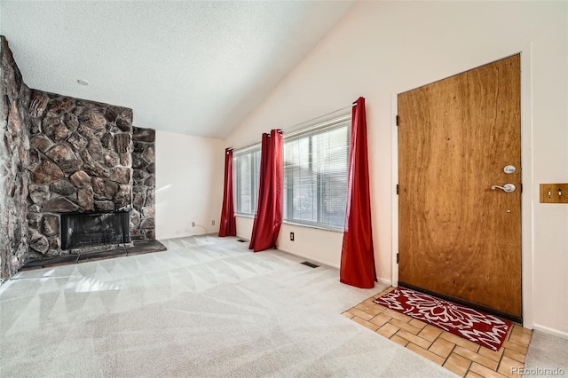 unfurnished living room featuring visible vents, a textured ceiling, carpet, a fireplace, and lofted ceiling