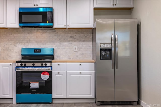 kitchen featuring white cabinetry, butcher block countertops, decorative backsplash, and appliances with stainless steel finishes