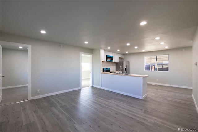 kitchen featuring hardwood / wood-style floors, tasteful backsplash, sink, white cabinets, and kitchen peninsula