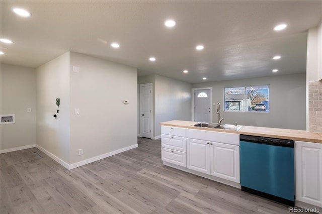 kitchen with stainless steel dishwasher, butcher block counters, sink, and white cabinets