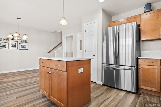 kitchen featuring hardwood / wood-style flooring, a center island, pendant lighting, and stainless steel refrigerator