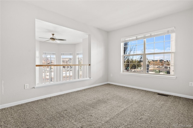 empty room with carpet flooring, a wealth of natural light, and ceiling fan