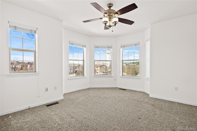 empty room with ceiling fan, carpet flooring, and a wealth of natural light