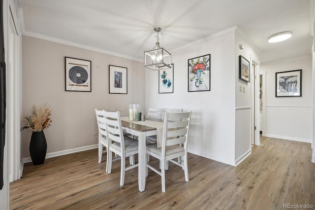 dining room featuring baseboards, a chandelier, ornamental molding, and wood finished floors