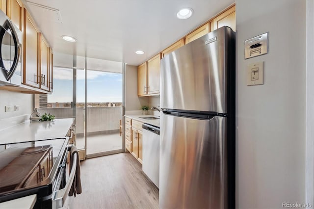 kitchen with a sink, light brown cabinets, light countertops, light wood-style floors, and stainless steel appliances