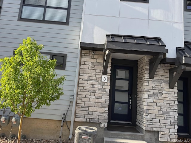 doorway to property featuring cooling unit and stone siding