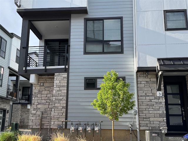 view of side of home with a balcony and stone siding
