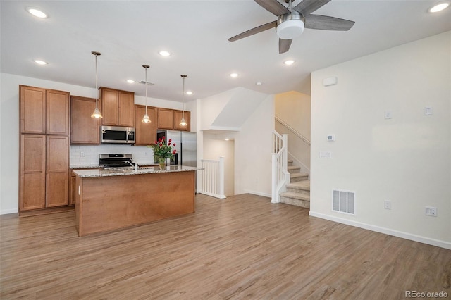 kitchen featuring recessed lighting, visible vents, light wood-style floors, stainless steel appliances, and an island with sink