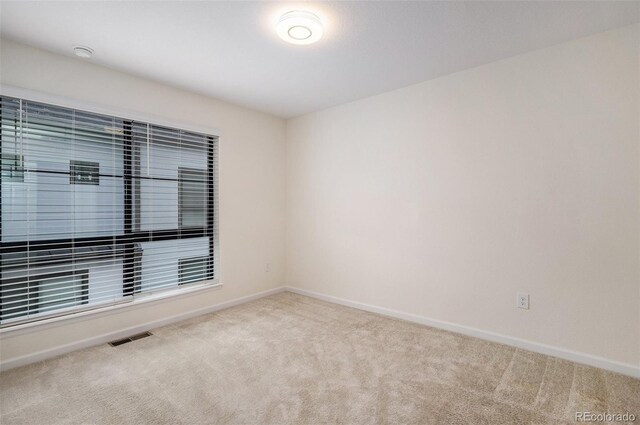 carpeted empty room featuring baseboards and visible vents