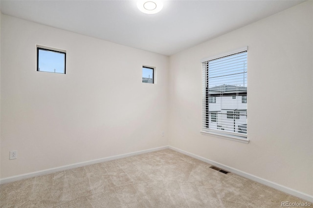 empty room with baseboards, a wealth of natural light, visible vents, and carpet floors