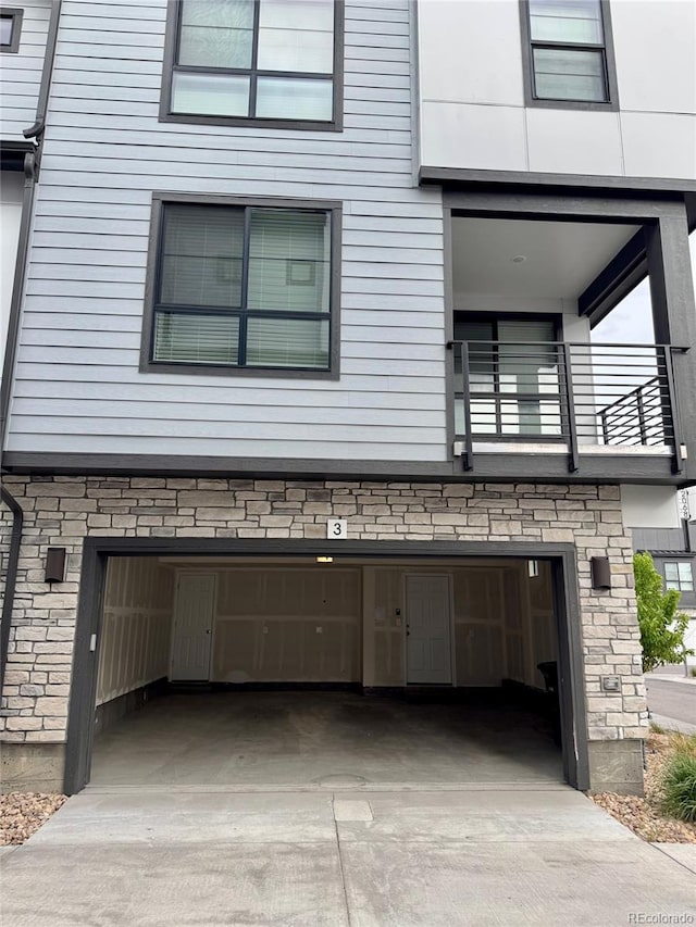 view of home's exterior featuring a balcony, driveway, and an attached garage