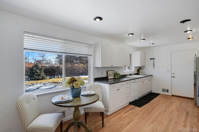 kitchen with white cabinetry, dishwasher, sink, stainless steel fridge, and light wood-type flooring