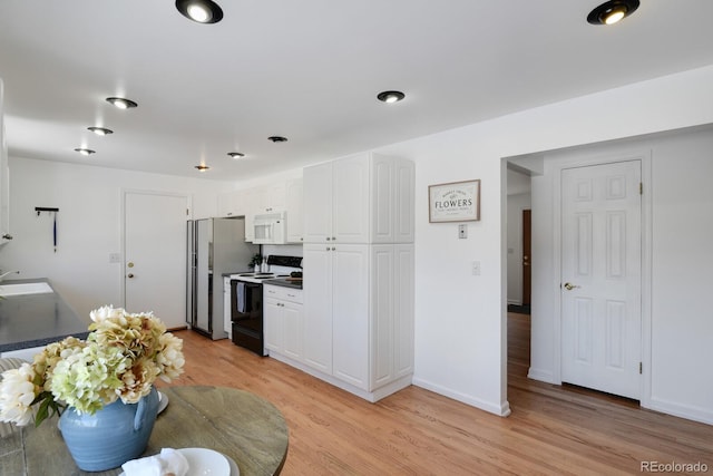 kitchen featuring sink, light hardwood / wood-style flooring, stainless steel refrigerator, white cabinetry, and electric range oven