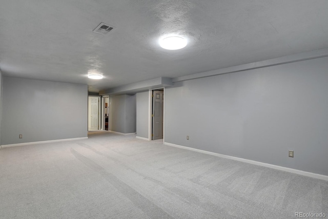 basement featuring light colored carpet and a textured ceiling