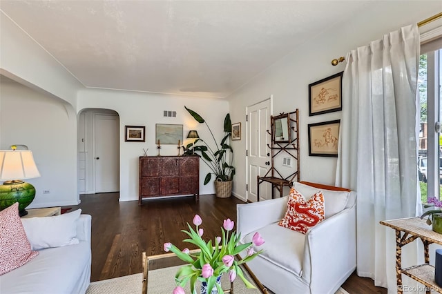 living area with arched walkways, wood finished floors, and baseboards