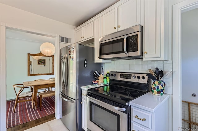 kitchen featuring appliances with stainless steel finishes, white cabinets, light countertops, and decorative backsplash