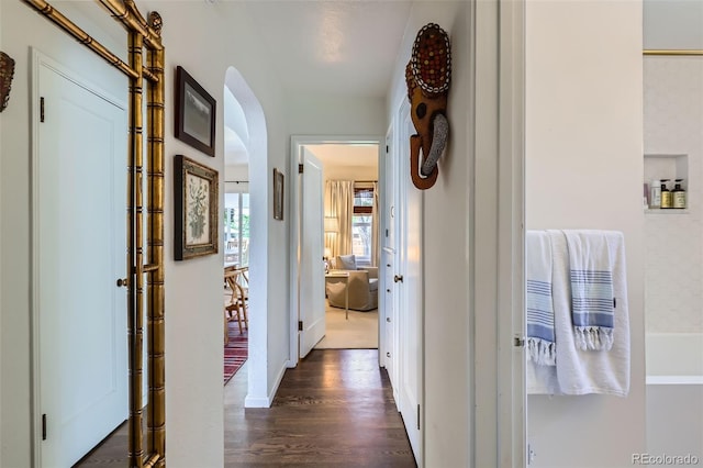 hallway with arched walkways and dark wood-type flooring