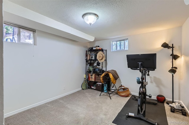 workout room featuring carpet flooring, a textured ceiling, and baseboards