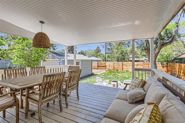wooden terrace with outdoor lounge area, an outbuilding, outdoor dining area, and a fenced backyard