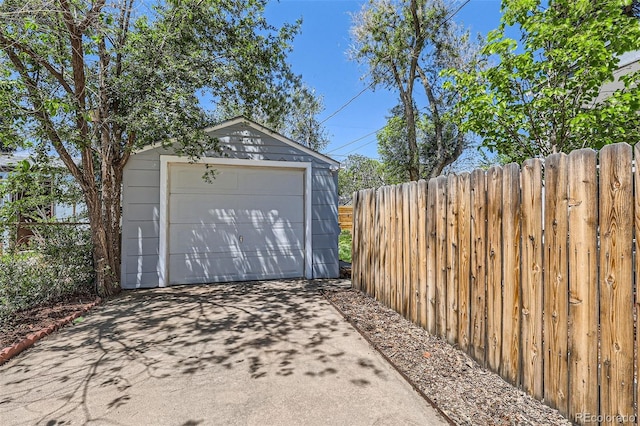 detached garage featuring driveway and fence