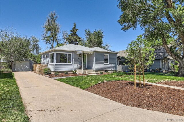 view of front of property with an outdoor structure, concrete driveway, a front yard, and a detached garage