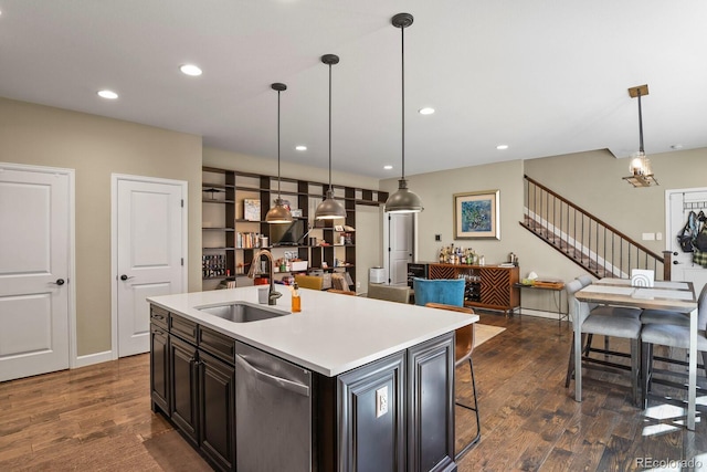 kitchen with sink, hanging light fixtures, stainless steel dishwasher, dark hardwood / wood-style floors, and a kitchen island with sink