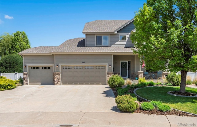 641 Denali Ct, Windsor, CO 80550 - view of front of home with an attached garage, driveway, stone siding, covered porch, and roof with shingles