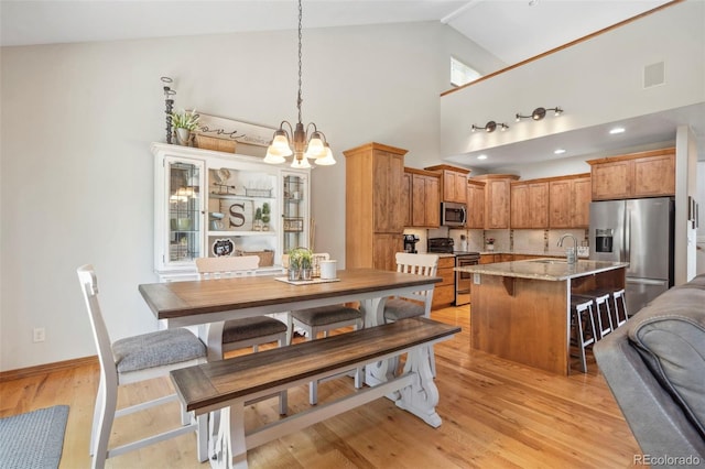 641 Denali Ct, Windsor, CO 80550 - dining room with a chandelier, high vaulted ceiling, light wood-style flooring, and baseboards