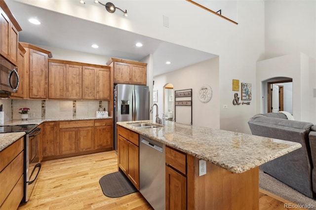 641 Denali Ct, Windsor, CO 80550 - kitchen featuring appliances with stainless steel finishes, arched walkways, a sink, light wood-style floors, and tasteful backsplash