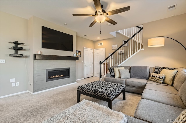 carpeted living room featuring ceiling fan and a tiled fireplace