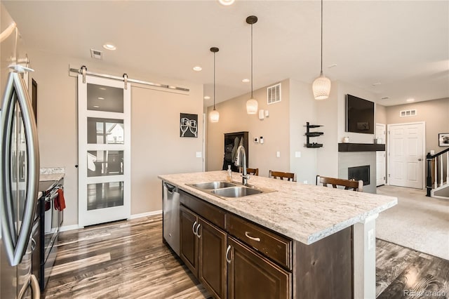 kitchen featuring pendant lighting, a barn door, sink, and appliances with stainless steel finishes