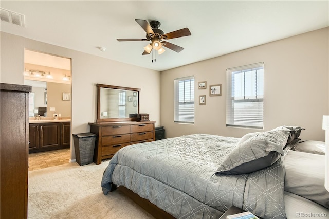 carpeted bedroom with ensuite bathroom, ceiling fan, and sink