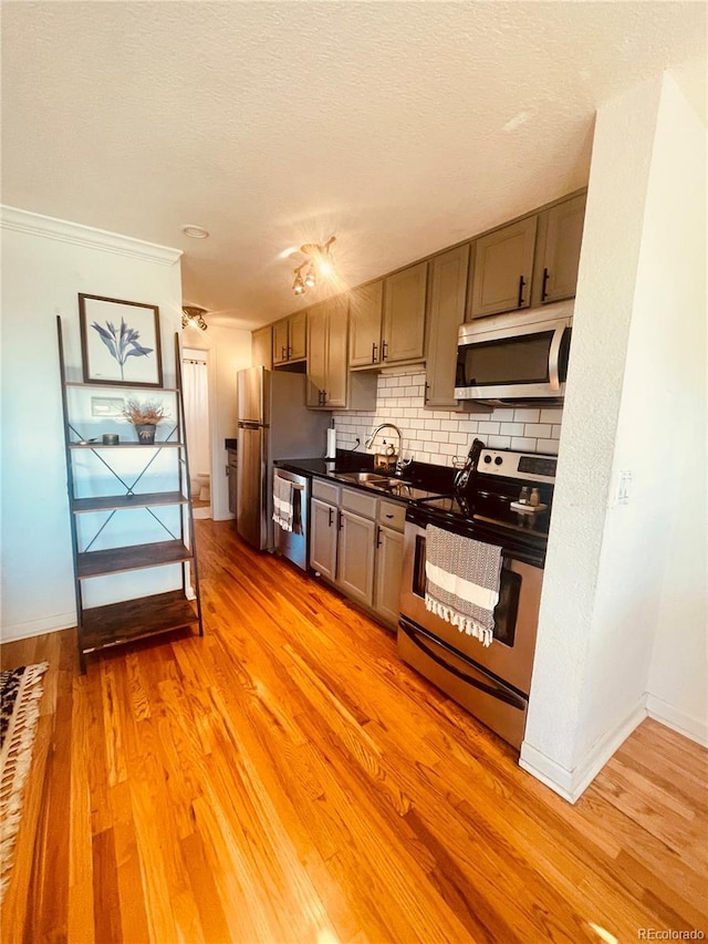 kitchen with sink, light hardwood / wood-style flooring, backsplash, appliances with stainless steel finishes, and ornamental molding