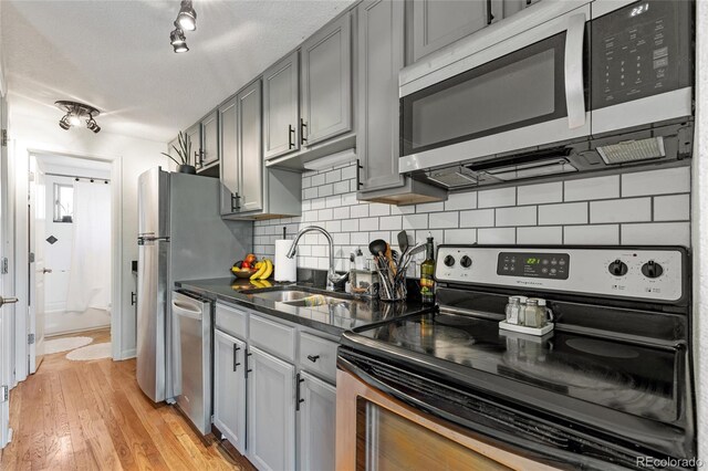 529 N Washington St Unit 304, Denver, CO 80203 - kitchen with stainless steel appliances, backsplash, a sink, light wood-style floors, and gray cabinets