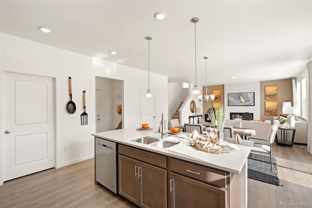 kitchen with stainless steel dishwasher, a sink, light wood-type flooring, light countertops, and recessed lighting