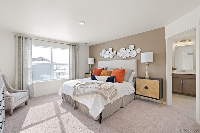 bedroom with light carpet, baseboards, and ensuite bathroom