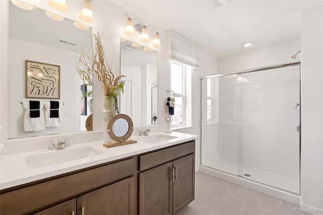 bathroom featuring a shower stall, tile patterned floors, and double vanity