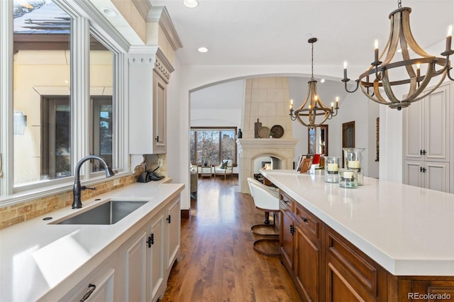 kitchen with a fireplace, white cabinetry, sink, backsplash, and a center island