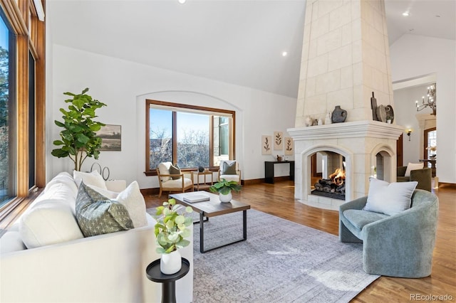 living room with a multi sided fireplace, hardwood / wood-style floors, a notable chandelier, and high vaulted ceiling