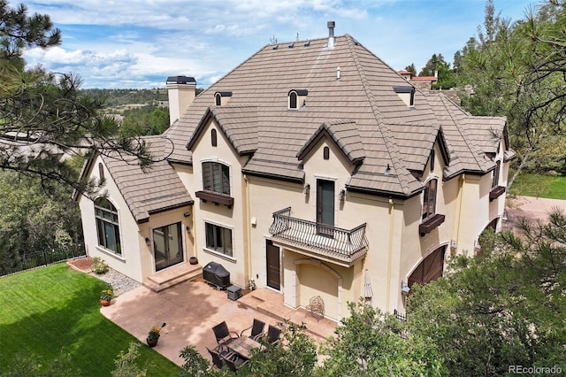 rear view of property featuring a yard, a patio, and a balcony